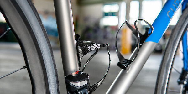 A pair of carbon Tune bottle cages on a custom-painted Curve Belgie titanium bicycle