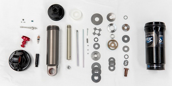 A disassembled bicycle rear shock, showing all of the small parts and internals