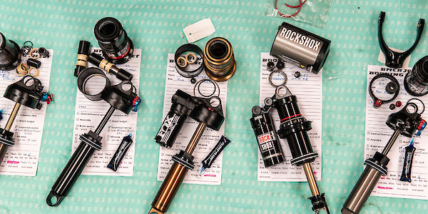 A line of bicycle rear shocks in pieces during the suspension servicing and repair process