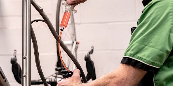 Bicycle mechanic bleeding bicycle disc brakes at Bio-Mechanics Cycles & Repairs