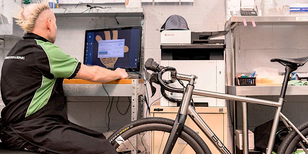Bicycle mechanic working at a computer to update the electronic system on a bicycle