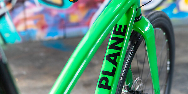 Frame detail on a custom-designed carbon Plane Frameworks bike, graffiti on the wall in the background