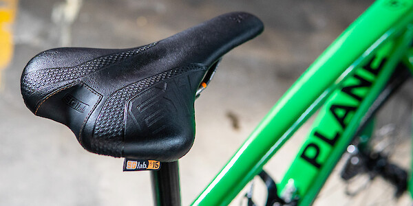 An SQ-Lab saddle fitted to a green carbon Plane Frameworks bike, viewed from above and to the side
