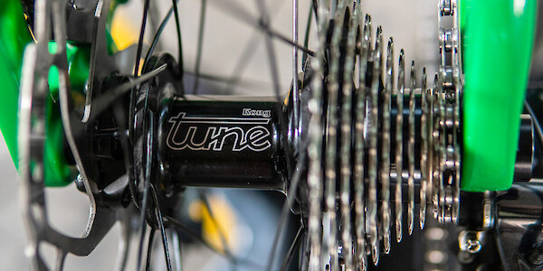Close-up of a Tune hub laced into a bicycle wheel, fitted to a green custom-designed carbon Plane Frameworks bike