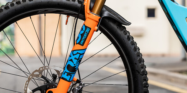 Orange and blue Fox suspension forks with custom decals on an Ibis Ripmo V2 MTB in Bug Zapper Blue