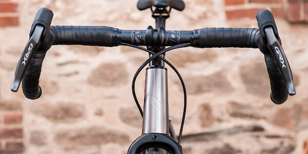 Handlebar and head tube detail on a Bossi Grit titanium gravel bicycle, shot from the front