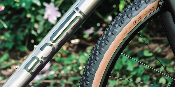 Frame decal detail on a Bossi Grit SX titanium bike, against a garden backdrop