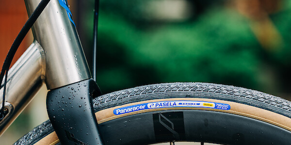 Frame and fork detail on a titanium Bossi Summit road bike, the hand-painted headtube decal matching the blue logo on the Panaracer tan sidewall tyre