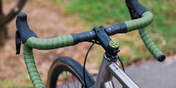 Handlebars on a Bossi Grit SX titanium bicycle, viewed from above to highlight the green Garbaruk top cap and matching Ciclovation handlebar tape
