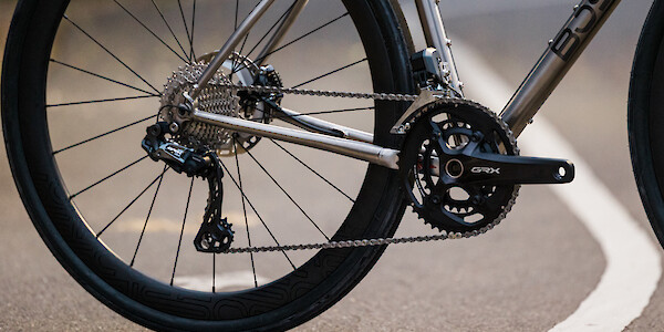 Drivetrain detail on a Bossi Grit SX titanium gravel bike, standing on a cycle path