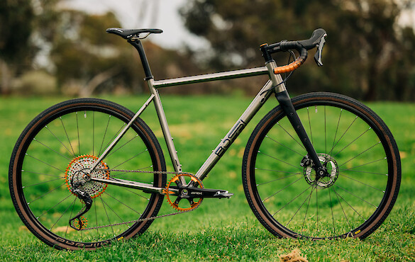 Custom-built Bossi Grit titanium bicycle against a backdrop of greenery