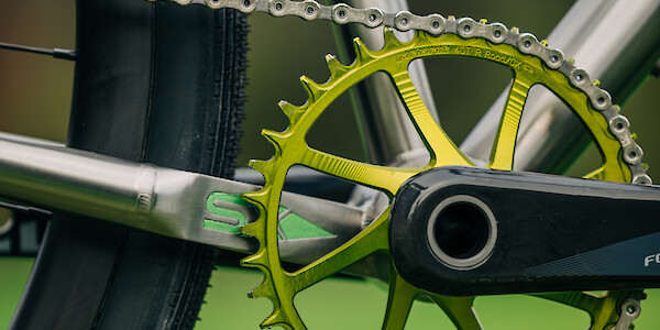 A green Garbaruk chain ring on a Bossi Grit SX titanium gravel bike, with hand-painted details visible on the frame