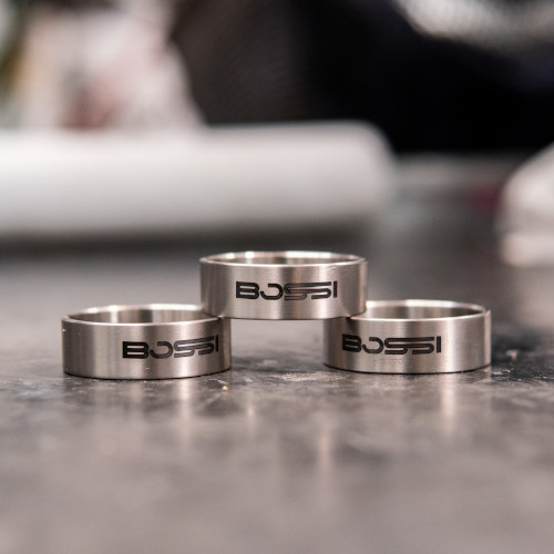A trio of titanium Bossi bicycle headset spacers on a granite surface