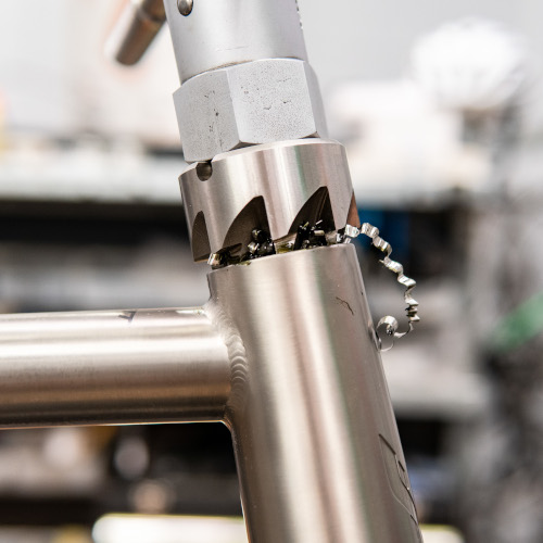 A titanium bicycle frame being faced with professional tools, swarf and grease visible