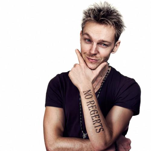 Smirking man with a 'NO REGERTS' tattoo