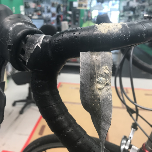 A bicycle handlebar with unwrapped bar tape, showing sweat deposits that have turned to powdered human sodium. It's pretty gross.