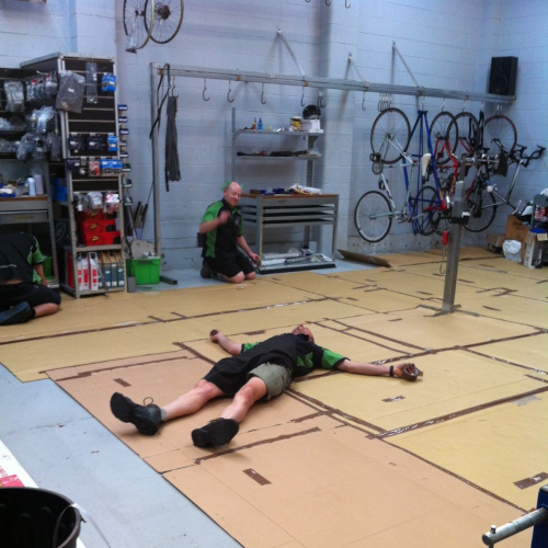 A mechanic lying spreadeagled on the floor at Bio-Mechanics Cycles & Repairs.