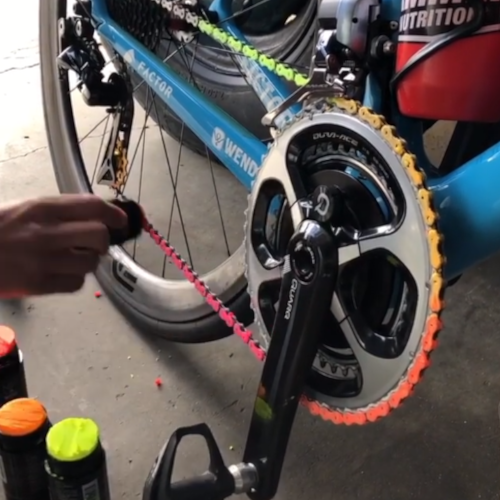 Someone applying coloured chain lube to a bicycle