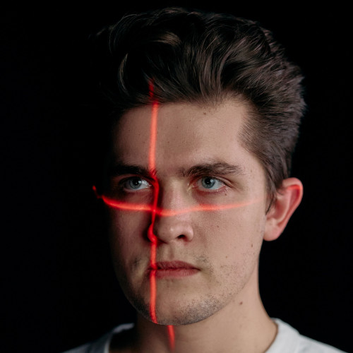 A man staring straight ahead, a red laser cross projected on his face