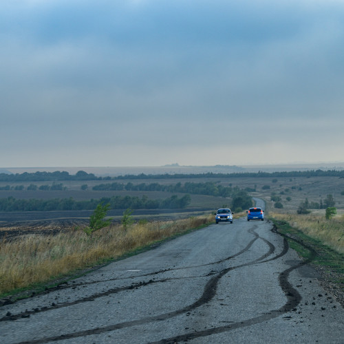 Two cars on a country road, a set of skid marks in the foreground