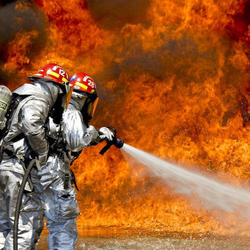 Fire-fighters spraying a wall of flames with a hose