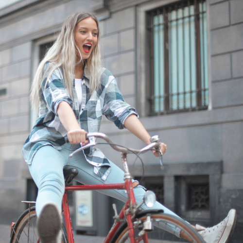 A young woman on a bicycle, with her legs out straight as if she's freewheeling down a slope. She looks happy enough.