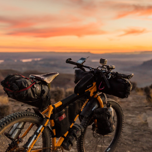 A steel bicycle laden with bikepacking bags, on a rocky outcrop