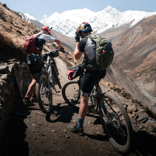 Two mountain bikers on a mountain pass, paused and checking their maps.