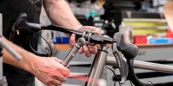 Bicycle mechanic using a torque wrench on a bicycle head stem