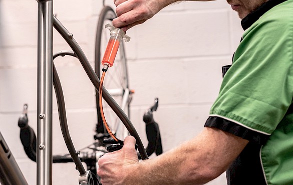 Bicycle mechanic bleeding bicycle disc brakes at Bio-Mechanics Cycles & Repairs
