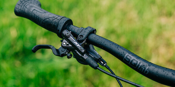 SQLab handlebars and SQLab 710 handlebar grips on a bicycle, photographed from above against a bright green lawn, drops of water visible.