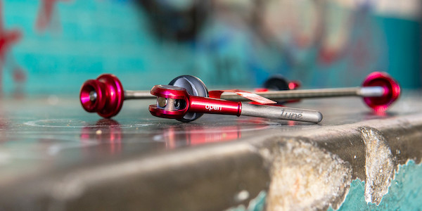Tune DC-130 quick-release skewers in red, lying on graffitied concrete