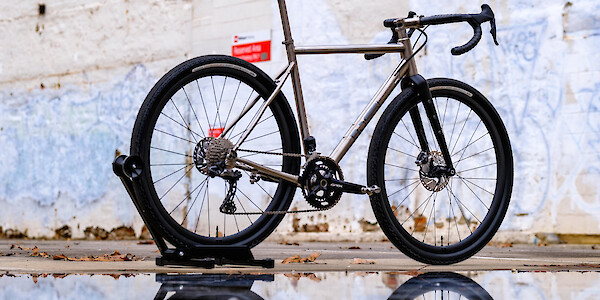 Bossi Grit SX titanium gravel bike, poetically mirrored in a puddle
