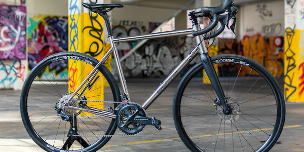 Bossi Summit titanium bicycle, standing inside a colourful graffitied car park with yellow pilons