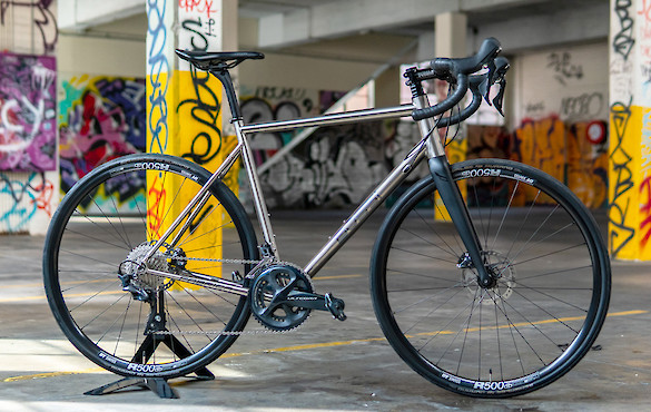 Bossi Summit titanium bicycle, standing inside a colourful graffitied car park with yellow pilons