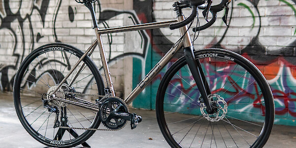Custom-built Bossi Summit titanium bicycle against a graffitied wall