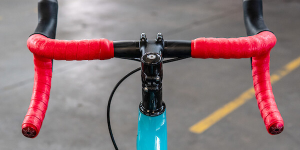 Zipp handlebars with red Supacaz handlebar tape on a blue Open Cycles Wide gravel bike, shot from the rider's point of view