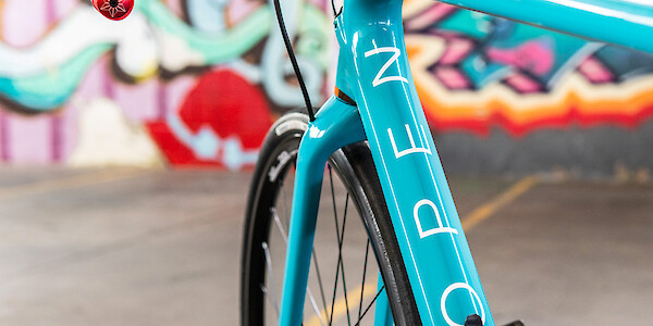 Frame decal detail on an Open WiDe gravel bicycle in blue, graffiti in the background