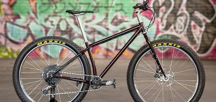 A Surly Krampus mountain bike in Pickled Beet, shot against a colourful graffitied wall