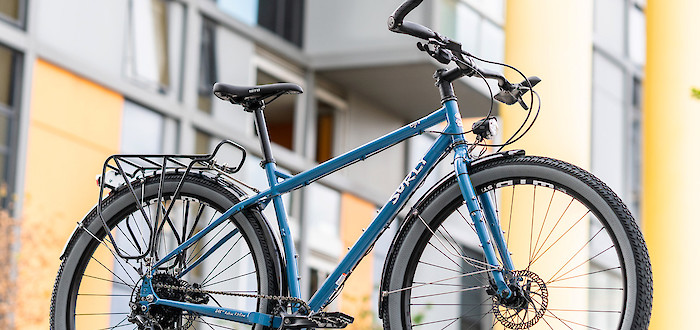 A custom-built Surly Ogre bicycle in Tangled Up In Blue, in front of a wall of apartment windows and viewed slightly from below