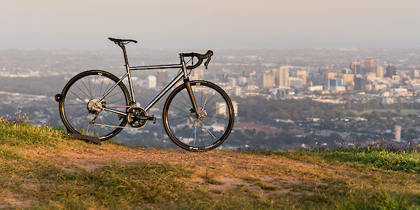 Bossi Strada Classic titanium bike, on a hill against a backdrop of the city of Adelaide, South Australia