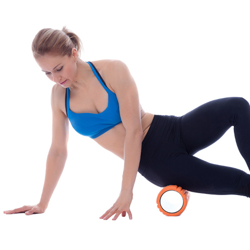 A woman in exercise gear using a foam roller on her lower hip