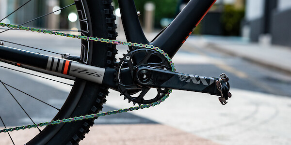 Crank, chain and chainring detail on an Ibis Cycles DV9 carbon bicycle, an industrial streetscape behind