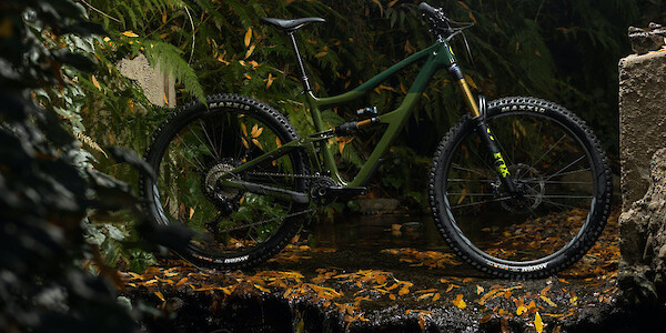 Ibis Ripmo V2S mountain bike in Bruce Banner Green, shot on a waterfall ledge. It looks kind of slimy, but cool.