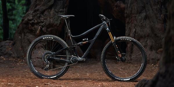 Ibis Ripmo V2S mountain bike in EnduroCell Black, shot against a moody forest landscape