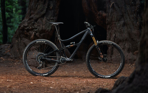 Ibis Ripmo V2S mountain bike in EnduroCell Black, shot against a moody forest landscape