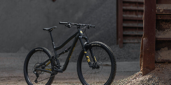 Ibis Cycles Ripley AF in Mustard Stain black, shown in a sandy industrial setting with moody lighting