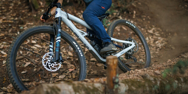 A mountain bike rider on a leafy trail on an Ibis Cycles Ripley AF in Protein Shake White