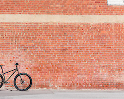 Long shot of a khaki Surly Ogre against a large expanse of brick wall in the bright sunshine