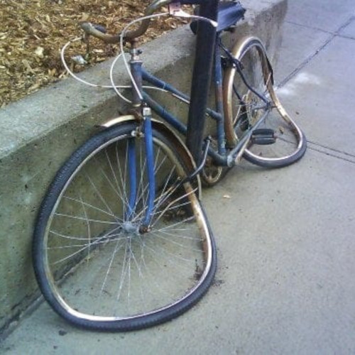 A bicycle that looks like its wheels have melted onto the ground.